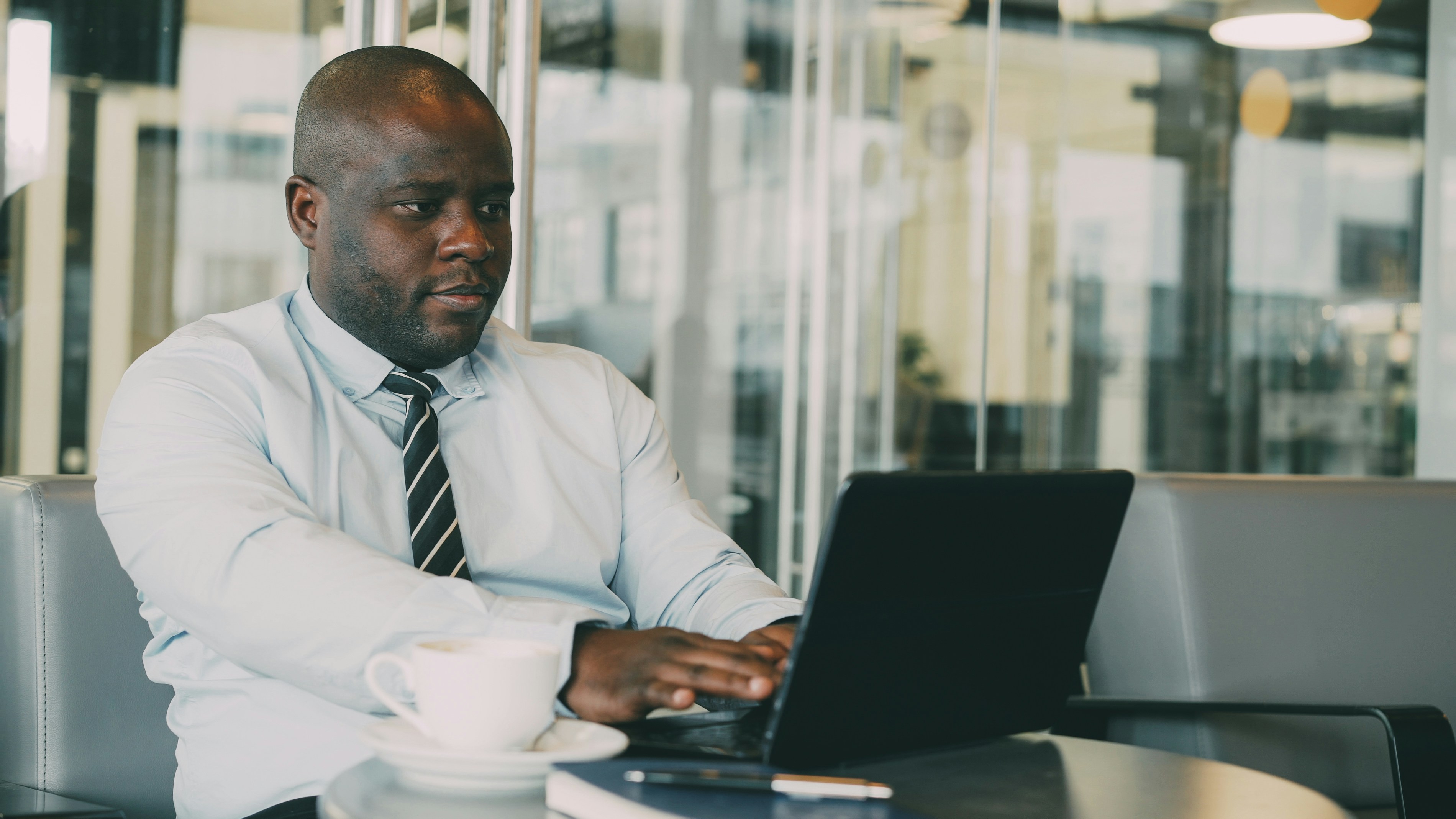 Man typing on laptop with coffee cup nearby